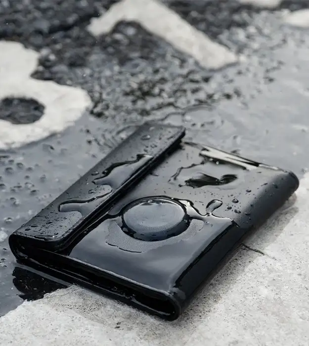 Kožni putni novčanik za pasoš sa ugrađenim Bluetooth trackerom, crne boje, položen na prtljag