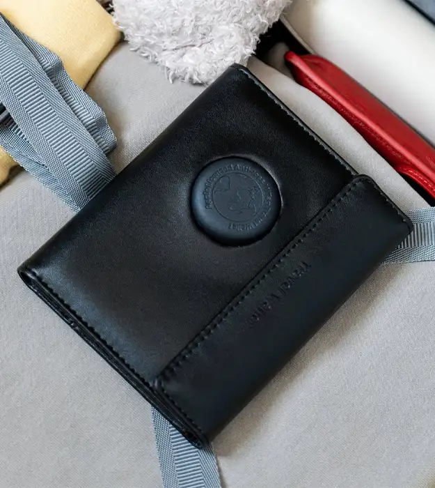 Kožni putni novčanik za pasoš sa ugrađenim Bluetooth trackerom, crne boje, položen na prtljag